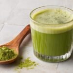 Friss zöldárpa italpor, egészséges zöld ital pohárban.