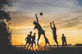 Sportolók homokkupacban, naplementében strandröplabdázva.