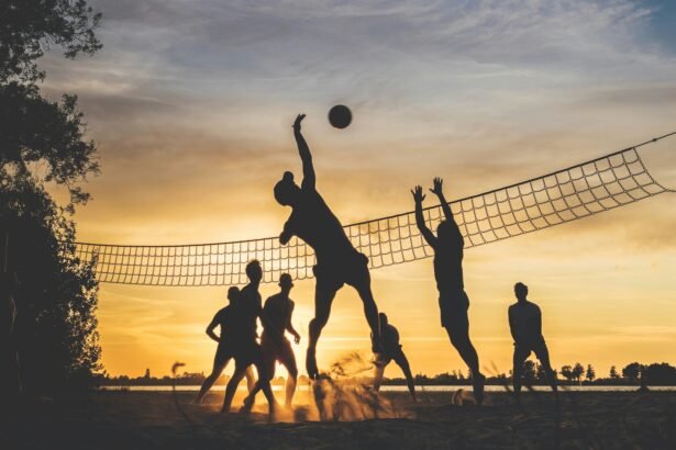 Sportolók homokkupacban, naplementében strandröplabdázva.